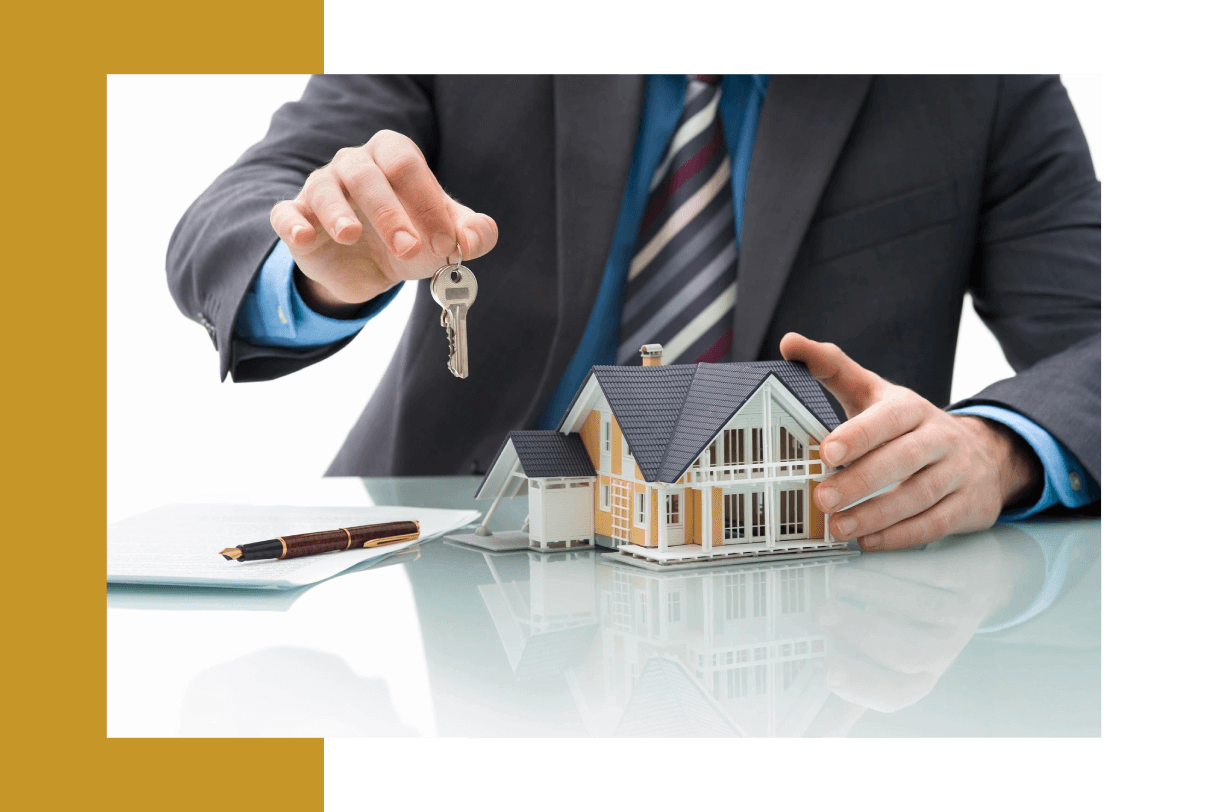 A man in a suit holding out keys to a house.